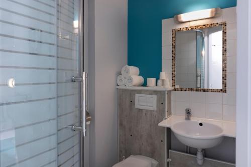 a bathroom with a sink and a toilet and a mirror at The Originals Access, Hôtel Innostar in Labège