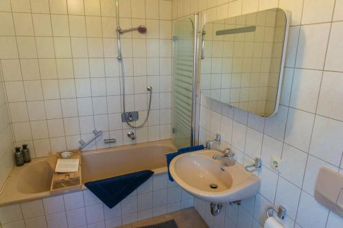 a bathroom with a sink and a tub and a mirror at Casa Burgplatz - Maisonettewohnung in Hüfingen