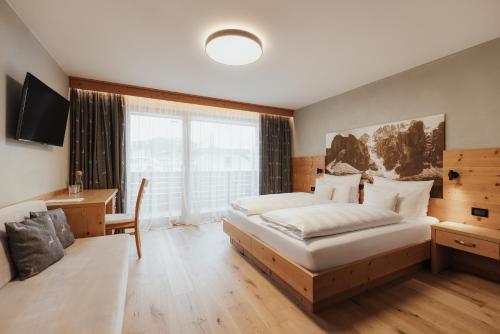 a bedroom with a bed and a desk and a window at Hotel Jägerhof in Colfosco