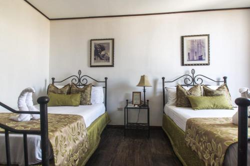 two beds in a room with white walls at Hotel Los Balcones Leon in León