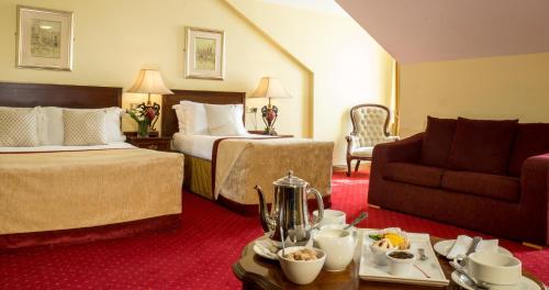 Habitación de hotel con 2 camas y sofá en Meadow Court Hotel en Loughrea