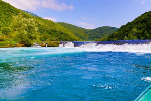 a river with blue water and a waterfall at Holiday Homes Mujo Bejzin in Račić