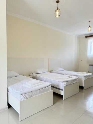 two beds in a room with white walls at Hotel Oasis in Kapan