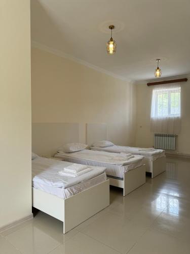 three beds in a room with white walls at Hotel Oasis in Kapan