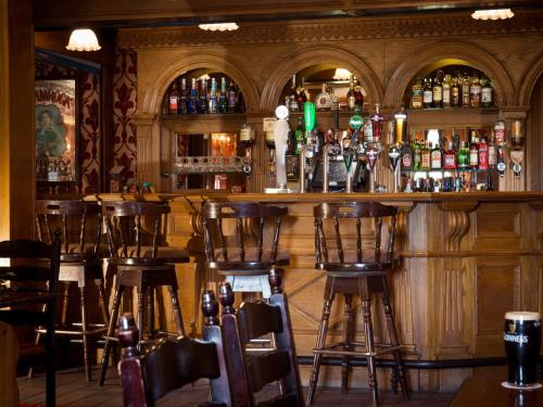 eine Bar mit Holzhockern in einem Zimmer mit Alkohol in der Unterkunft Meadow Court Hotel in Loughrea