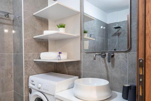 a bathroom with a sink and a washing machine at Sunny Rock Apartments in Asfendioú