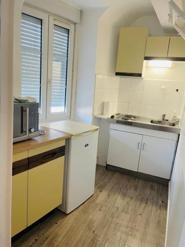 une cuisine avec des armoires blanches et un micro-ondes dans l'établissement Studio 8 rue de la République, à Orléans