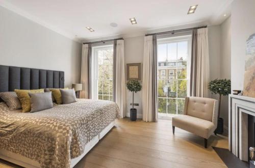 a bedroom with a bed and a chair and windows at Luxury 4 Bedrooms 5 Baths 2 Receptions Family House with Garden Chelsea in London
