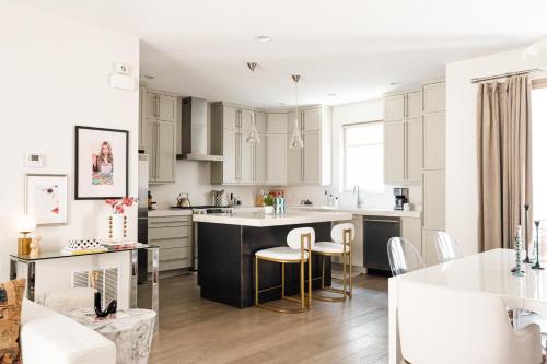 a kitchen with white cabinets and a kitchen island with bar stools at Vogue Posh Pad - Center of LoHi - Large Roof Deck in Denver