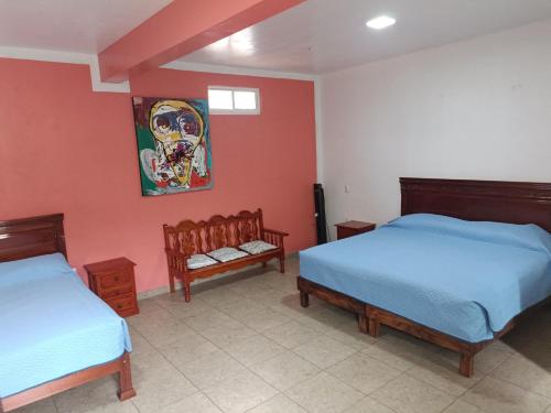 2 Betten in einem Zimmer mit roten Wänden in der Unterkunft Casa alebrijes in San Agustin de las Juntas