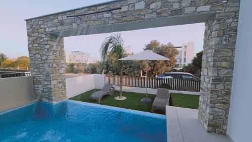 a swimming pool with a patio and an umbrella at STAY Oasis Luxury Villas in Ayia Napa