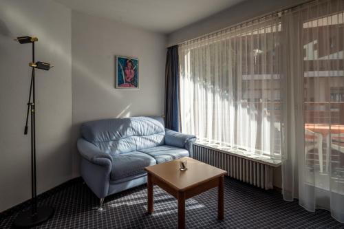 a living room with a blue chair and a table at dala Hotel & Apartments in Leukerbad