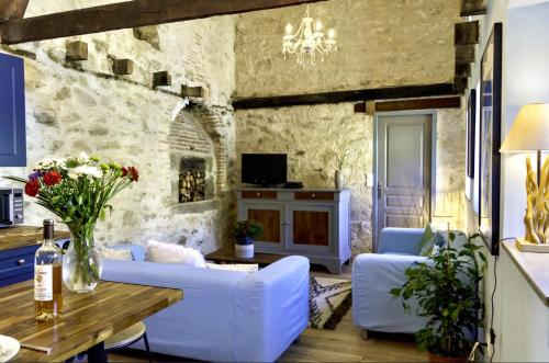 a living room with white furniture and a stone wall at Petite Maison de Mouton in Azat-le-Riz