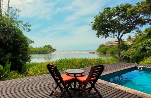 a table and two chairs on a deck with a view of a river at Finca Barlovento Maloka, Tayrona Park in Los Naranjos