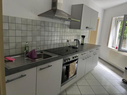 una cucina bianca con lavello e fornello di Monteurswohnung Ferienwohnung in der Mitte Deutschlands nahe der A3 a Hünfelden