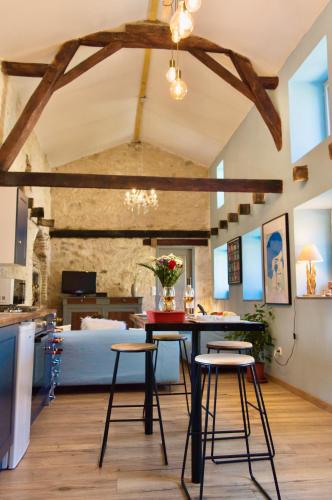 une cuisine avec une table et des tabourets dans une pièce dans l'établissement Petite Maison de Mouton, à Azat-le-Riz