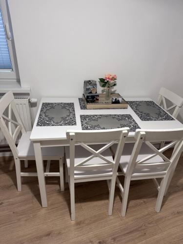 a white table and chairs with a table and flowers at Apartament Szczecinek in Szczecinek