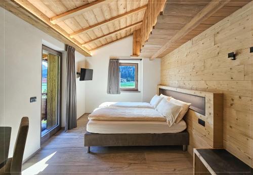 a bedroom with a bed and a wooden wall at Agriturismo Bosco d'oro Livigno in Livigno