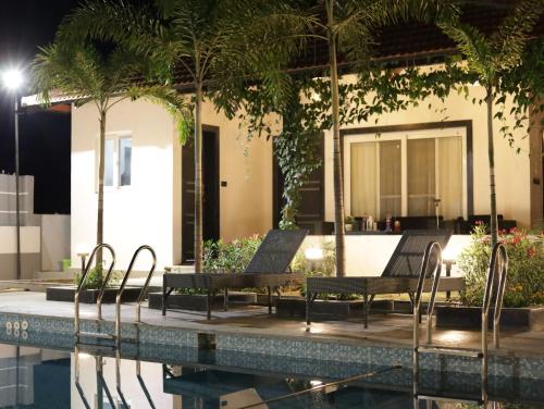 a resort with a pool and chairs next to a building at Button Eyes Resort - Pet friendly in Hyderabad