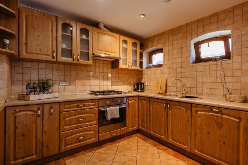 a kitchen with wooden cabinets and a stove top oven at B10 Dom LUX z Alpakami & Basen SPA in Ełk