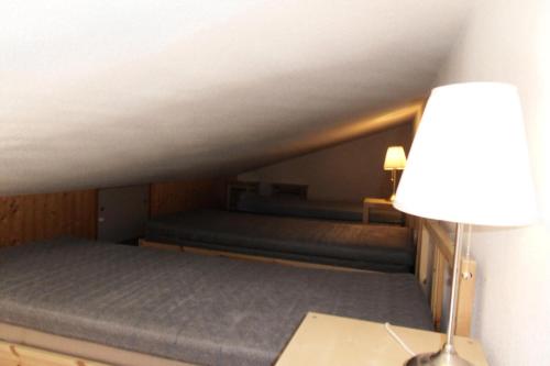 Cette chambre mansardée comprend des lits superposés et une lampe. dans l'établissement Résidence Carene - 2 Pièces pour 5 Personnes 79, à Mâcot La Plagne