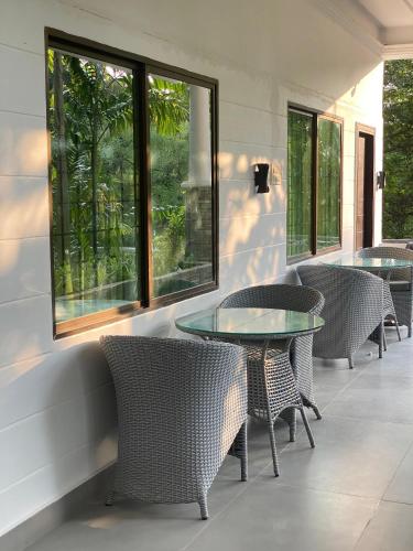a patio with chairs and a glass table and windows at Button Eyes Resort - Pet friendly in Hyderabad