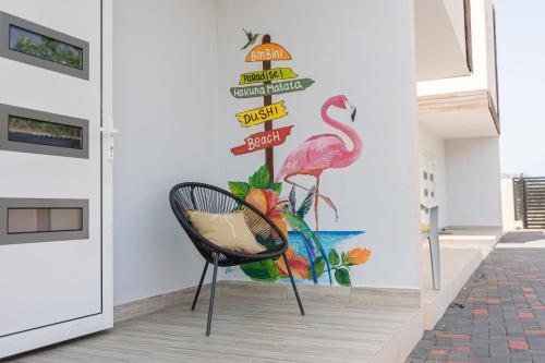 a chair in front of a wall with a flamingo sign at Av Curacao - Centrally Located Spacious Apartment in Willemstad