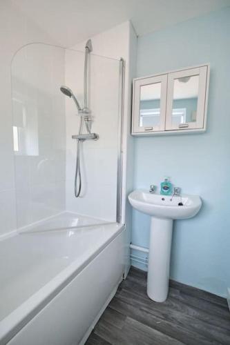a white bathroom with a sink and a shower at Olivia Cottage - a Home From Home by the Sea in Morecambe