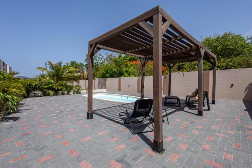 a wooden pavilion with two chairs and a pool at Av Curacao - Centrally Located Spacious Apartment in Willemstad