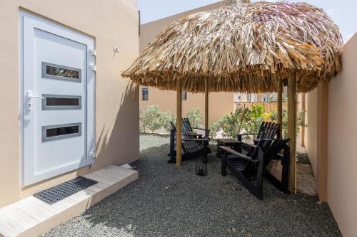 a group of chairs under a straw umbrella at Av Curacao - Centrally Located Spacious Apartment in Willemstad