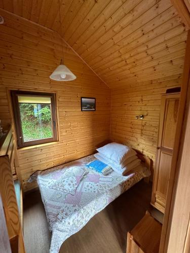 a small bedroom with a bed in a wooden cabin at Bieszczady Pod Dębem Solina in Solina