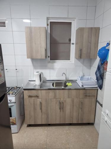 une cuisine avec des armoires en bois, un évier et une cuisinière dans l'établissement Maca Apartments, à Willemstad
