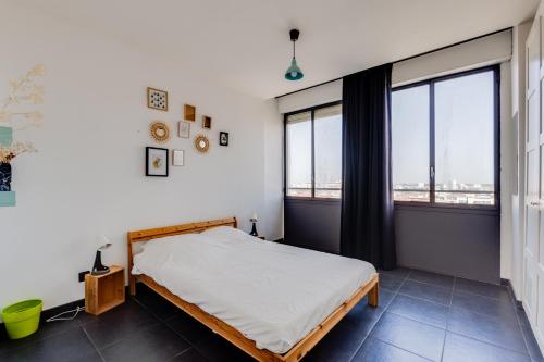 une chambre avec un lit et deux grandes fenêtres dans l'établissement Le Panoramique - Ramblas Jean-Jaurès, à Toulouse