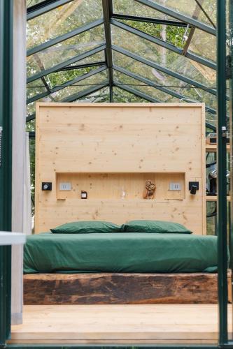 a bed in a wooden room with a glass ceiling at Vivi la Magia di Bisdalù - Dormi nella Stanza nel Bosco, Ammira le Stelle e Rilassati con l'Area Benessere e Colazione in Peveragno