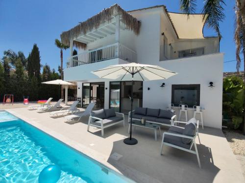 una villa con piscina con sillas y sombrilla en Five Palms Villa, en Paphos