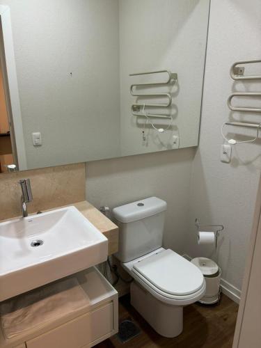 a bathroom with a white toilet and a sink at Flat em Gramado in Gramado