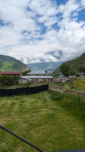 a field of green grass with a building in the background at Rest point cottage Kazbegi in Stepantsminda