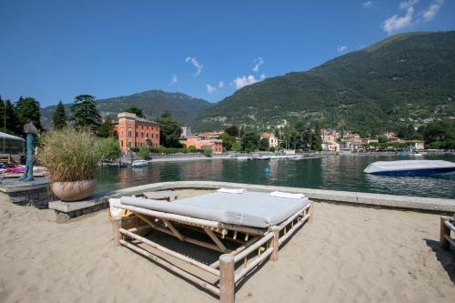 a bed sitting on a beach next to a body of water at Lenno Giardinetto in Lenno