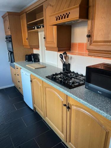 a kitchen with wooden cabinets and a stove top oven at Milton Keynes Comfort Haven in Haversham