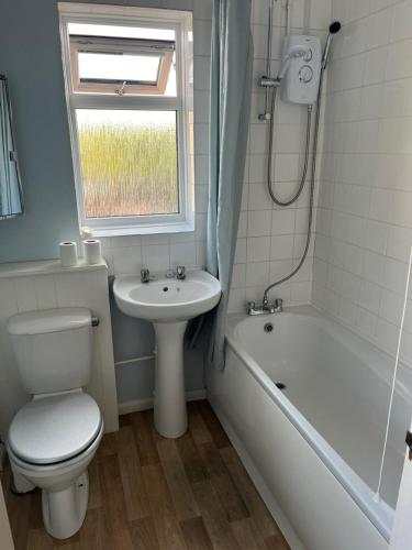 a bathroom with a toilet and a sink and a bath tub at Milton Keynes Comfort Haven in Haversham