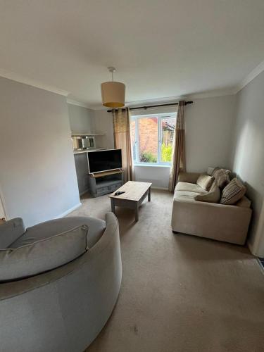 a living room with a couch and a table at Milton Keynes Comfort Haven in Haversham