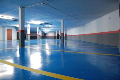 an empty parking garage with a blue floor and white walls at Apartamentos Boabdil in Sierra Nevada
