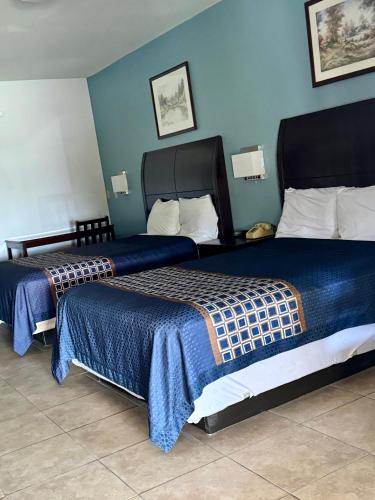 two beds in a hotel room with blue walls at Texas Inn and Suites City Center at University Dr. in Edinburg