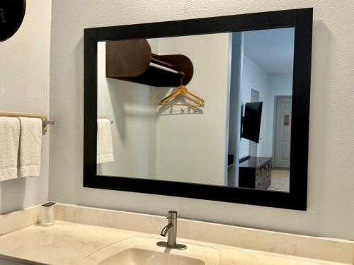 a mirror above a sink in a bathroom at Texas Inn and Suites City Center at University Dr. in Edinburg