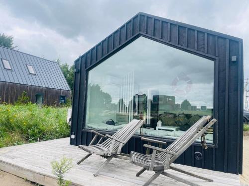 two chairs sitting on a deck in front of a building at Jaukus mikro namas Svencelėje in Svenele