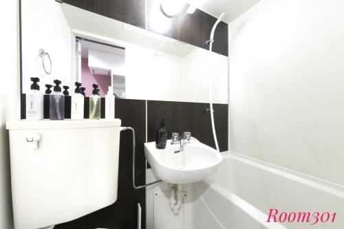 a white bathroom with a sink and a bath tub at SLEEPLAB THE STAY Casual 西新宿 in Tokyo