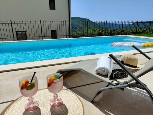 two martini glasses on a table next to a swimming pool at Villa Lea Marezige Heated Pool near Koper in Marezige