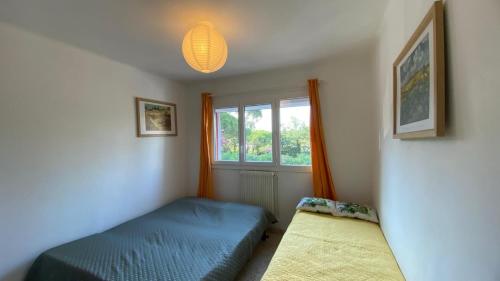 une chambre avec un lit bleu et une fenêtre dans l'établissement T3 en REZ-DE-JARDIN sur VALESCURE, à Saint-Raphaël