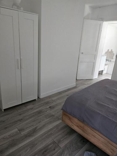 une chambre blanche avec un lit et des armoires blanches dans l'établissement Ma location plage dunkerque, à Dunkerque