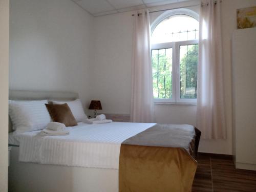 a white bedroom with a large bed and a window at Moravska Obala - Prenoćište i Restoran in Velika Plana